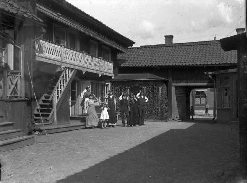 Bostadshus, hemmet på Kungsgatan 33, Lindesberg. Grupp sju personer framför huset, troligen solförmörkelsen den 21 augusti 1914.